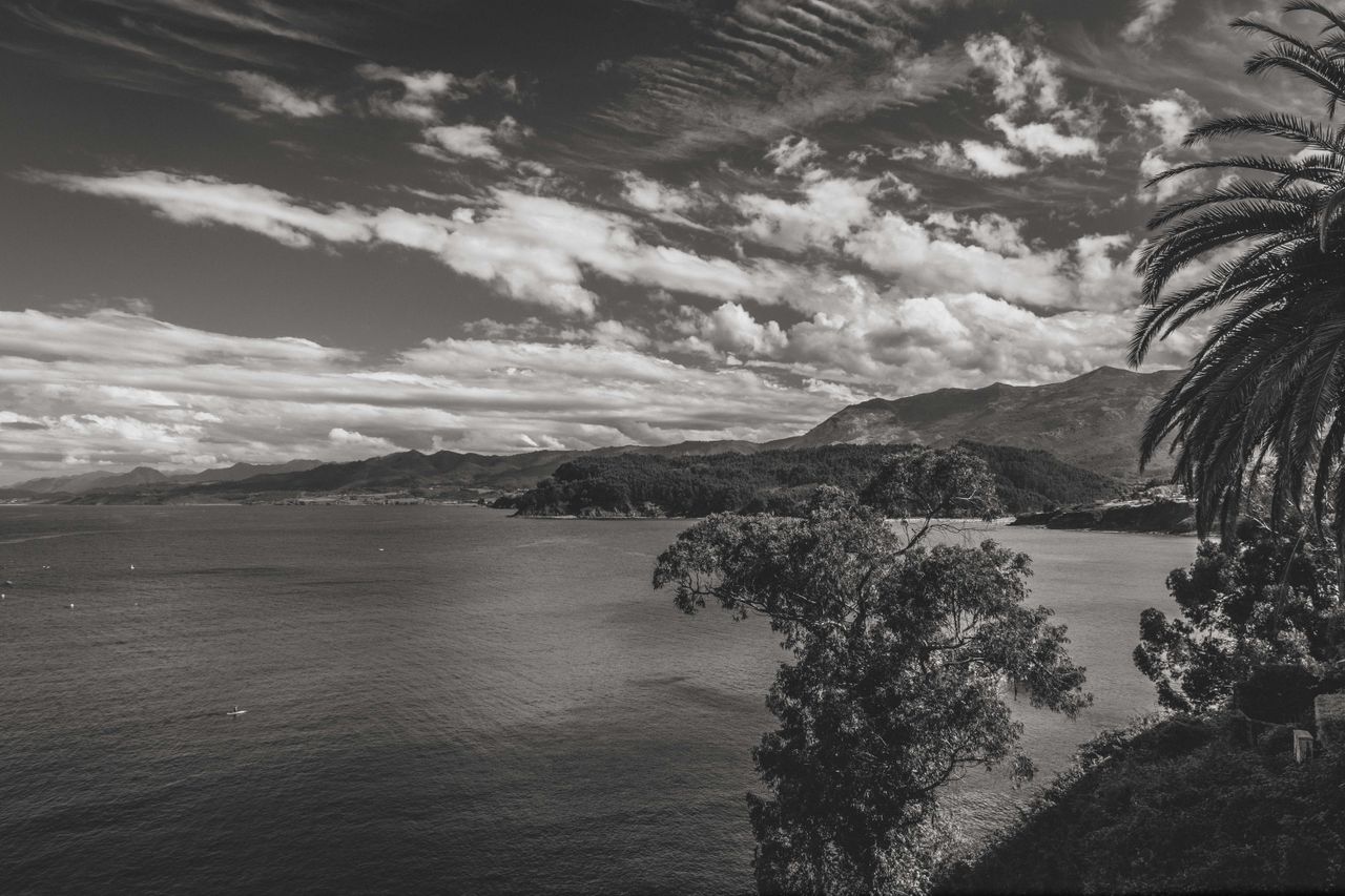 A captivating black and white landscape of Lastres coastline with mountains and the sea under dramatic clouds.